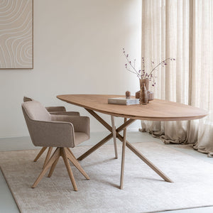 Organische eiken eettafel met beige Mikado-onderstel en beige Hofu-stoelen, schuin van voren in een licht interieur.